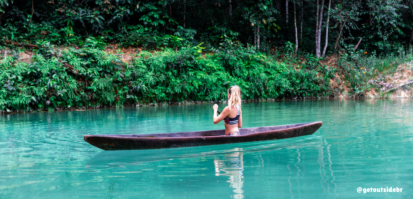 Mulher sentada em um barco em uma lagoa azul em Presidente Figueiredo