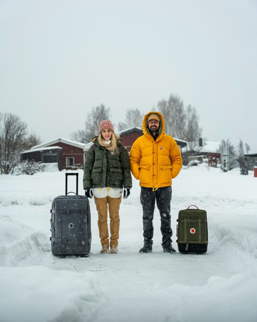 Ale e Duda usando roupas e malas Fjällräven durante uma viagem na neve, experiência que embasa as recomendações do cupom Fjällräven GET10.