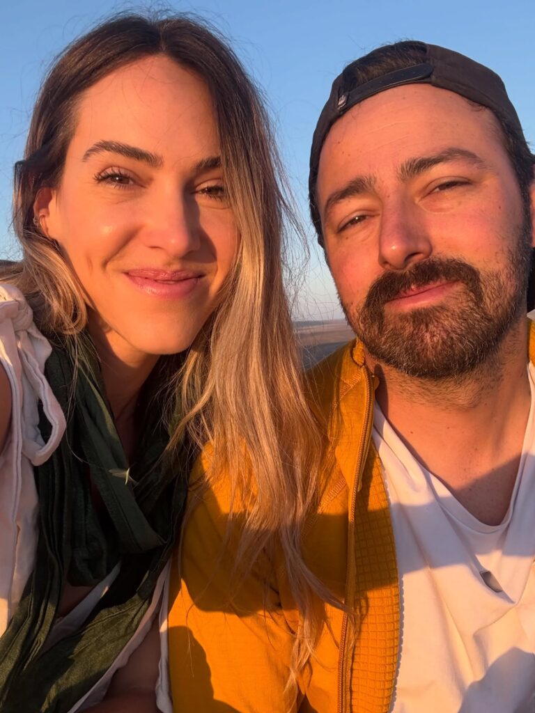 Ale e Duda durante uma viagem em ambiente ensolarado, compartilhando a experiência com os produtos da Pink Cheeks.