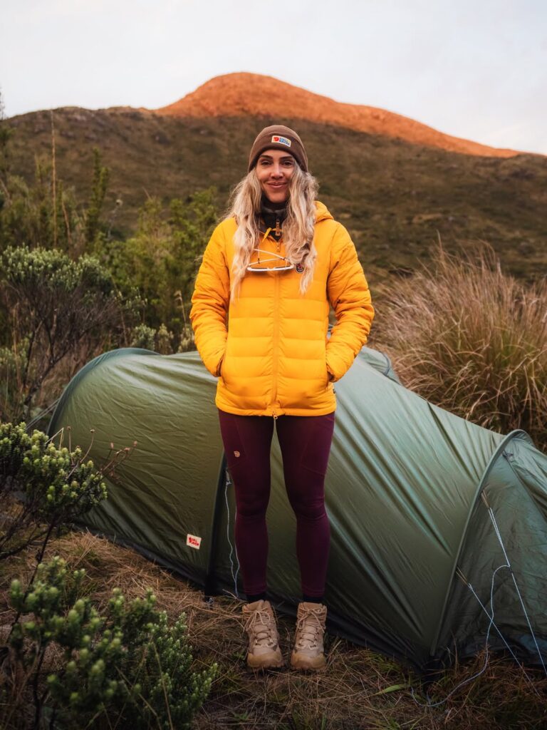 Duda usando jaqueta Fjällräven em ambiente de montanha durante uma viagem, mostrando o uso da marca em clima frio e atividades outdoor.